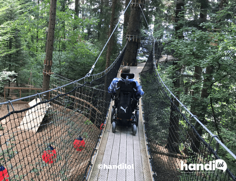 Fauteuil roulant sur un pont suspendu d'accrobranche. Photo de l'association handilol.